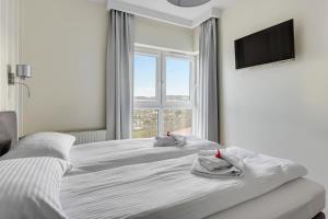 a white bedroom with two beds and a window at Wave Apartments - Albatros in Gdańsk