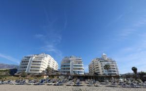 a group of buildings on a beach with chairs at Banana Beach primera línea de playa in Marbella