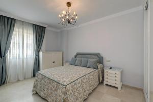 een slaapkamer met een bed en een kroonluchter bij Banana Beach primera línea de playa in Marbella