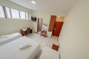 a hotel room with two beds and a desk at Hotel Metropolitano in Coronel Fabriciano