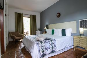 a bedroom with a large bed with blue walls at Pousada Arvoredo in Pirenópolis