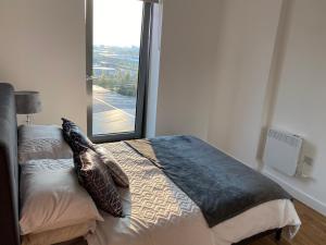 a bedroom with a bed with pillows and a window at 1 bedroom lovely apartment in Salford quays free street parking subject to availability in Manchester