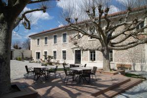 a patio with tables and chairs in front of a building at Castel serein in Maubec