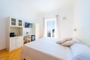 a white bedroom with a white bed and a window at Casa Pietro in Positano