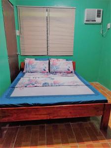 Bett in einem Zimmer mit grüner Wand in der Unterkunft La Frezza Beach House in Bayawan