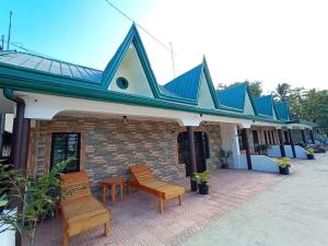 a building with two wooden benches in front of it at La Frezza Beach House in Bayawan