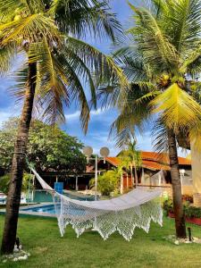 a hammock between two palm trees next to a pool at Paracuru Kitefriends Lux Pousada in Paracuru