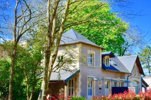 une grande maison blanche avec un toit bleu dans l'établissement Le Clos des Marronniers, à Douvres-la-Délivrande