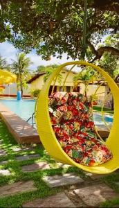 un columpio amarillo colgando de un árbol junto a una piscina en Paracuru Kitefriends Lux Pousada, en Paracuru