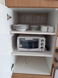 a microwave in a kitchen shelf with dishes at Ferienwohnung in Erftstadt in Erftstadt