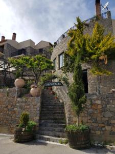 un edificio de piedra con escaleras y árboles delante de él en Αργουλιάς, en Tzermiádon