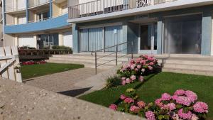 een tuin met roze bloemen voor een gebouw bij Concorde plage in Le Touquet-Paris-Plage