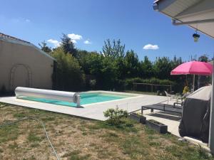 a swimming pool in a yard with a pink umbrella at Le Teich Tranquille in Le Teich