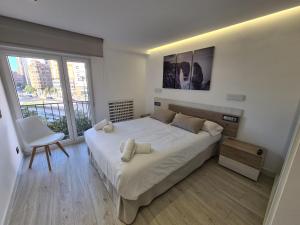 a bedroom with a large white bed and a chair at 104A Apartamento para 8 personas in Gijón