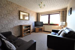 a living room with a couch and a television at Balcarres Self Catering in Fort William