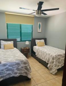 a bedroom with two beds and a ceiling fan at Mar Azul Bay View Apartment in Boqueron