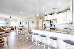 a kitchen and living room with white cabinets and bar stools at Wineaux Chateaux in Bolivar Peninsula