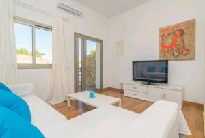 uma sala de estar com mobiliário branco e uma televisão de ecrã plano em Babamas 2 em Son Serra de Marina