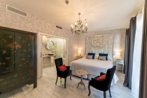 a bedroom with a bed and chairs and a chandelier at El Rey Moro Hotel Boutique in Seville