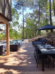 um deque com mesas e guarda-sóis e uma piscina em Agréable Villa Domaine du Golf Piscine CHAUFFEE em Biscarrosse