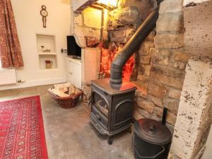 a fireplace with a wood stove in a room at Beehive Cottage in High Bentham