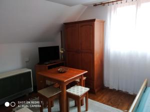 um pequeno quarto com uma mesa de madeira e uma televisão em Apartman Ana em Mokra Gora