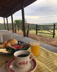 a table with a cup of coffee and a glass of orange juice at Pousada Xodó in São Pedro