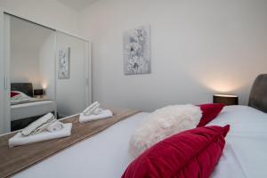 1 dormitorio con cama blanca con almohadas rojas y espejo en Ponente Apartments, en Dubrovnik