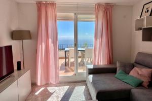 - un salon avec un canapé et une grande fenêtre dans l'établissement Fantástico apartamento con vistas panorámicas al mar, à Cumbre del Sol