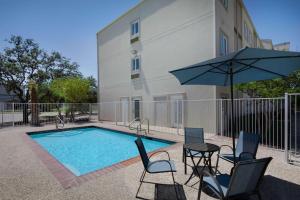 a pool with chairs and a table and an umbrella at Motel 6-San Antonio, TX - Airport in San Antonio
