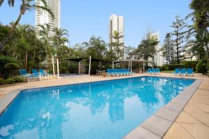 une grande piscine avec des chaises bleues et des palmiers dans l'établissement BreakFree Beachpoint, à Gold Coast