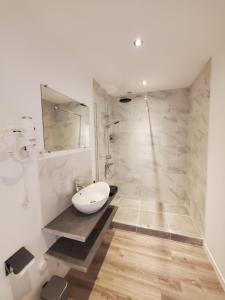 bagno bianco con lavandino e doccia di LE PIED A TERRE a La Châtre