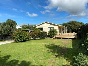 a house with a bench in the yard at Hibiscus House - Mangawhai Heads Holiday Home in Mangawhai