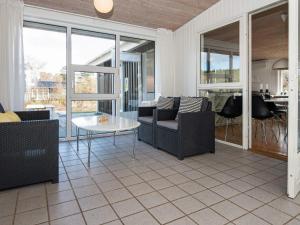 a living room with chairs and a table and windows at 8 person holiday home in Ebeltoft in Ebeltoft
