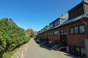 ein Backsteingebäude mit einem Gehweg neben einer Mauer in der Unterkunft Eva in Westerland