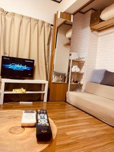 una sala de estar con 2 mandos a distancia sobre una mesa en COCO Nakameguro301 en Tokio