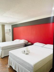 duas camas num quarto de hotel com uma parede vermelha em Maharajah Hotel em Angeles