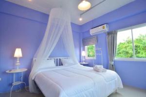 a blue bedroom with a white bed and a window at Day II Hotel in Ang Sila