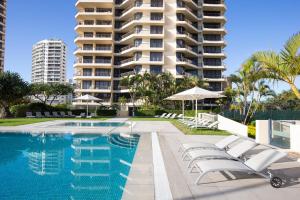 une piscine avec des chaises longues et un grand bâtiment dans l'établissement Paradise Centre Apartments, à Gold Coast