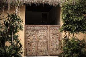 una entrada a una casa con una puerta de madera en Hotel Casa Hormiga en Bacalar