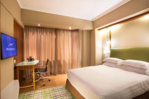 香港的住宿－粵海華美灣際酒店，酒店客房配有一张床、一张书桌和一台电视。