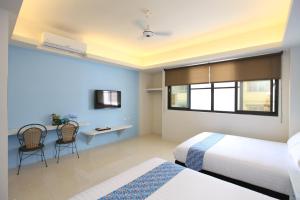 a bedroom with two beds and a desk with chairs at 安平72號民宿 in Tainan