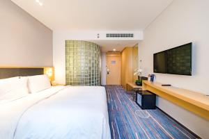 石家荘市にあるHoliday Inn Express Shijiazhuang Heping, an IHG Hotelの大型ベッド1台、薄型テレビが備わるホテルルームです。