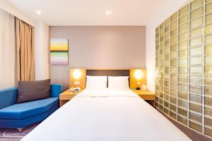 a hotel room with a large bed and a blue couch at Holiday Inn Express Shijiazhuang Heping, an IHG Hotel in Shijiazhuang