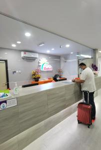 un hombre parado en un mostrador de hotel con una maleta en MORNINGS HOTEL, en Sungai Petani