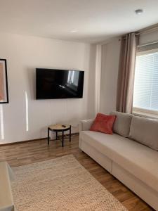 a living room with a couch and a tv on the wall at Cosy apartment in the city center in Kemi
