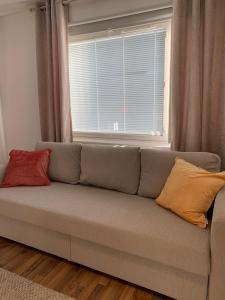 a couch with two pillows sitting in front of a window at Cosy apartment in the city center in Kemi