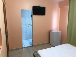 a bedroom with a glass shower with a television on the wall at Hotel Goiânia in Goiânia