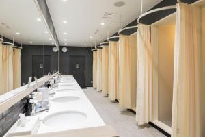 une rangée de lavabos dans une salle de bains commune dans l'établissement TUBE Sq, à Chūbu