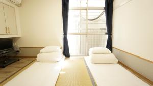 una sala de estar con 2 almohadas blancas y una ventana en House Ikebukuro en Tokio